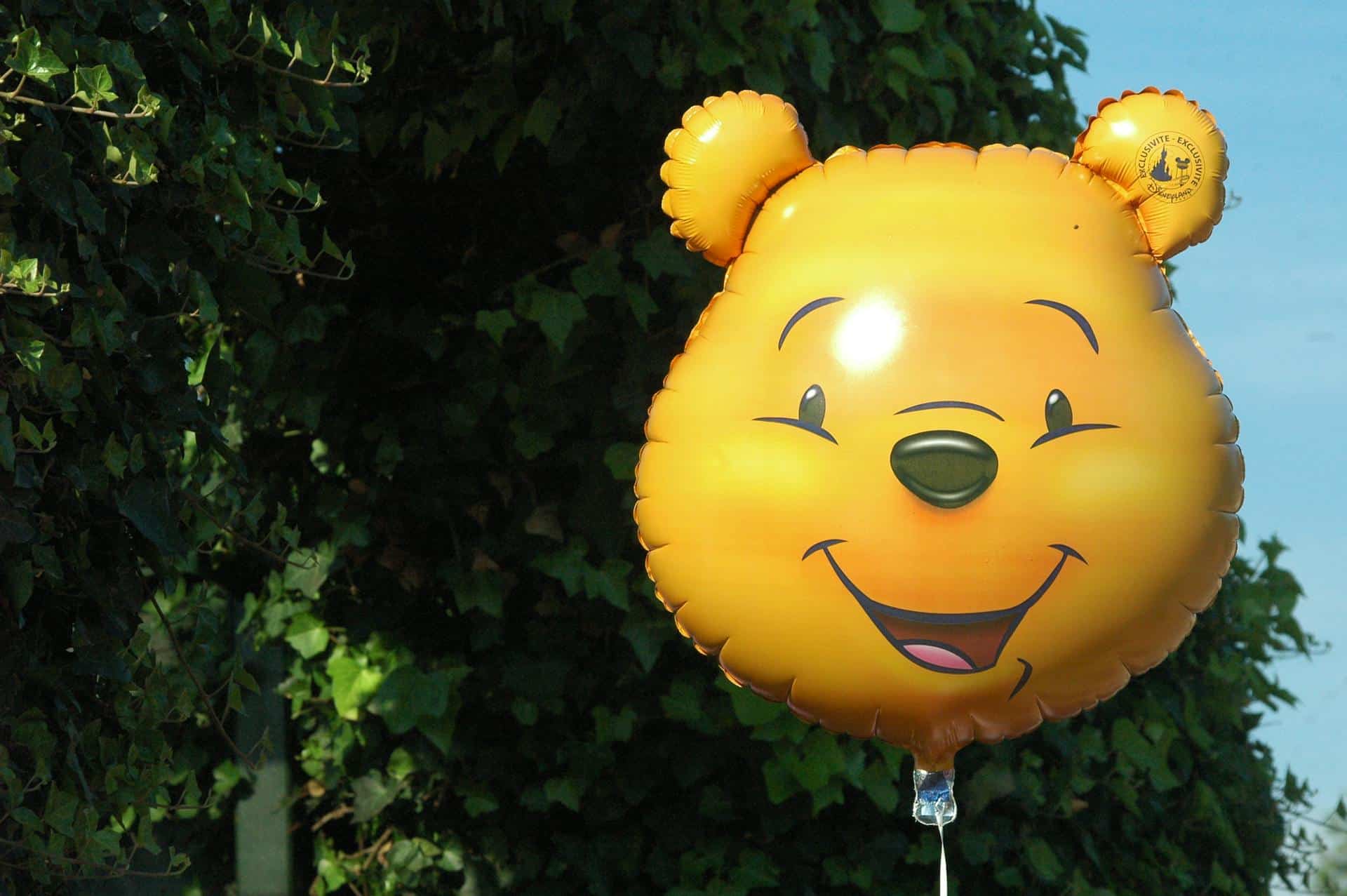 Winnie the Pooh ballon voor een achtergrond van groene bladeren.